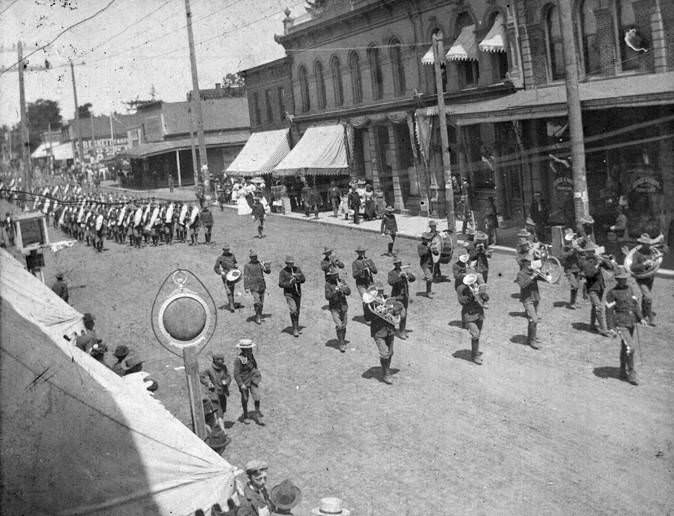 Military marching band parading down a street in Vancouver, Washington in 1906.