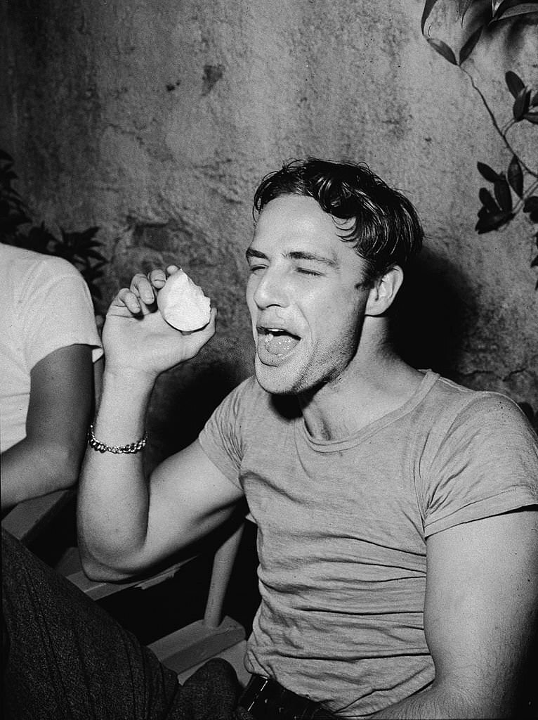 Marlon Brando laughs while eating an apple during a break on the set of the film, 'A Streetcar Named Desire, 1951