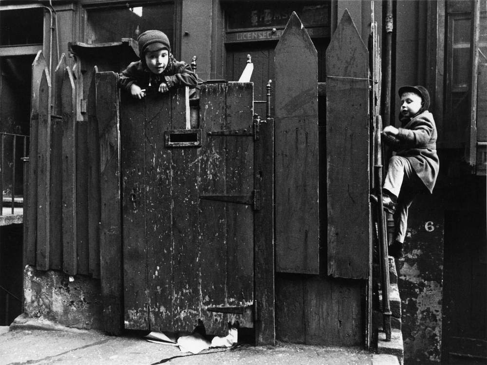 Children climbing fencse outside the pub, Edinburgh, 1965