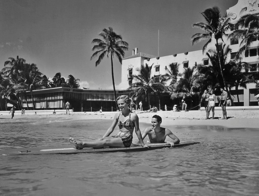 A man pushes a woman out to sea on a surf board, Waikiki Beach, Honolulu, Hawaii, 1955