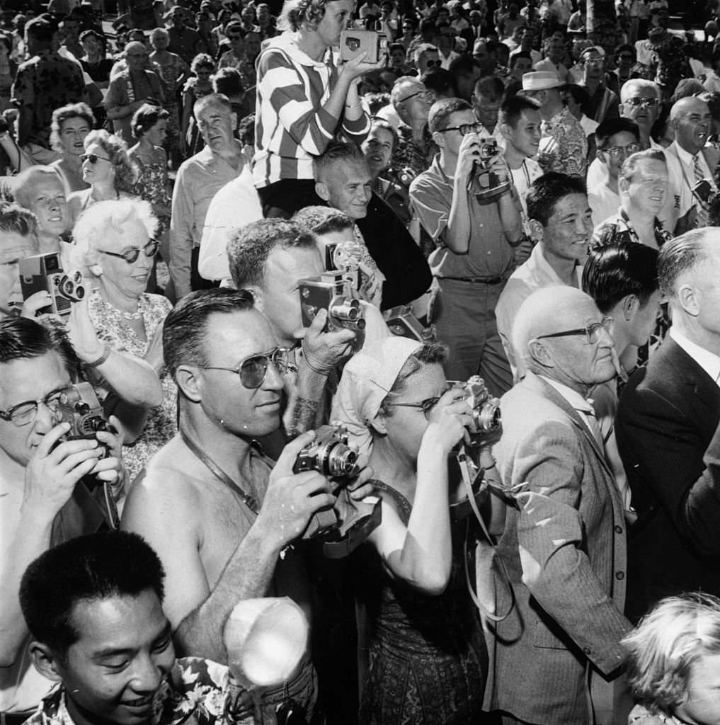 A crowd of camera wielding tourists watching a hula show in Honolulu, Hawaii, 1955