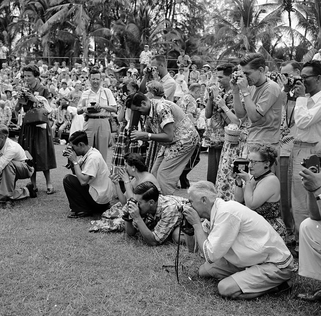 A group of tourists, poised with cameras at the ready for the arrival of the Hula dancers on Honolulu's Waikiki Beach, in Hawaii, 1953