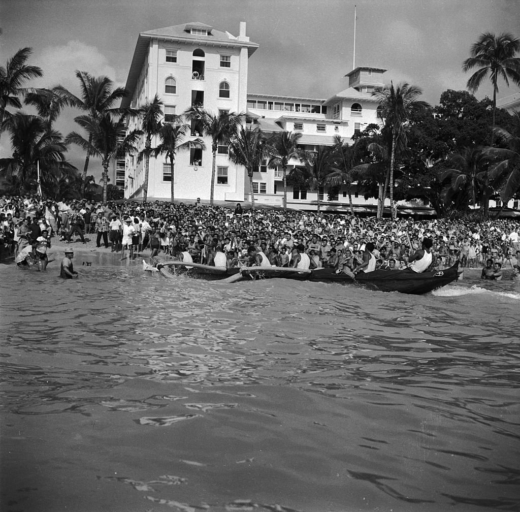 Crowds gather on the Hawaiian island of Oahu to watch the winning boat of a gruelling 36 mile canoe race arrive at the finish, 1950