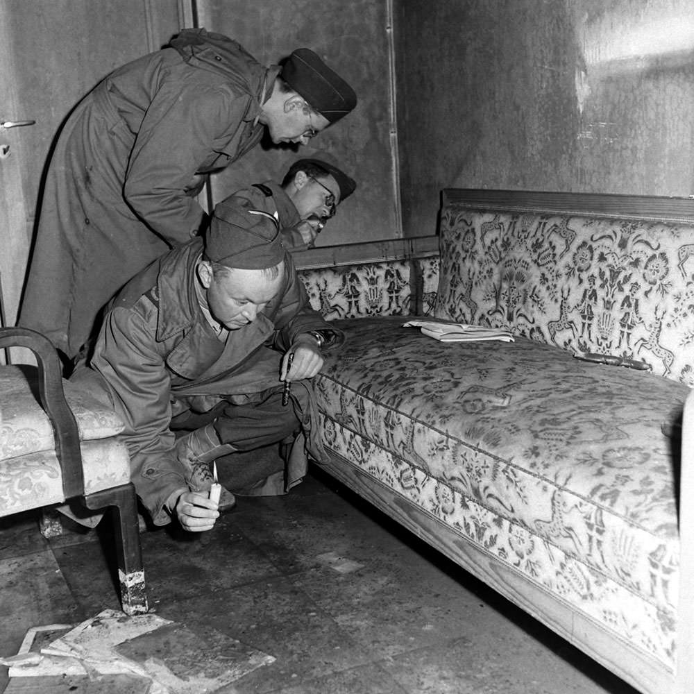 With only candles to light their way, war correspondents examine a couch stained with blood (see dark patch on the arm of the sofa) located inside Hitler's bunker.