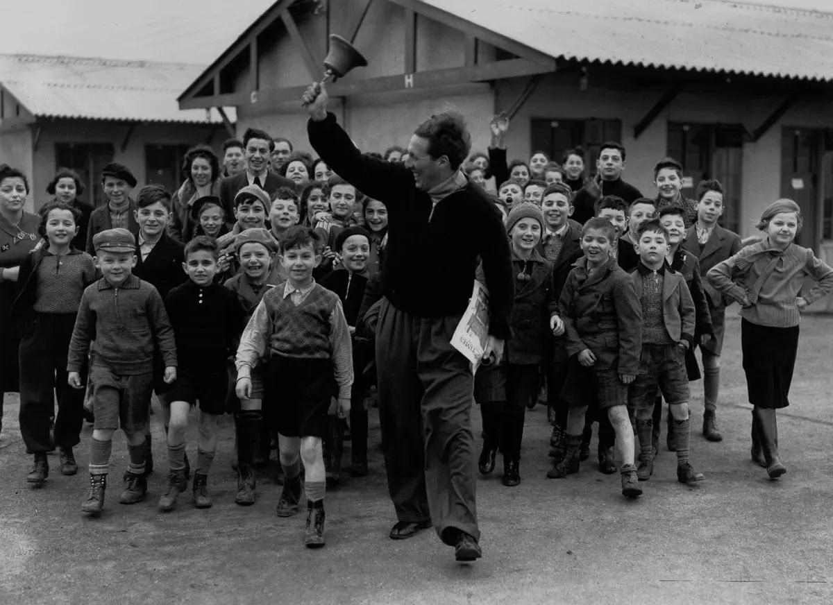 A camp leader rings the dinner bell for refugees at the Dovercourt holiday camp, 1939.