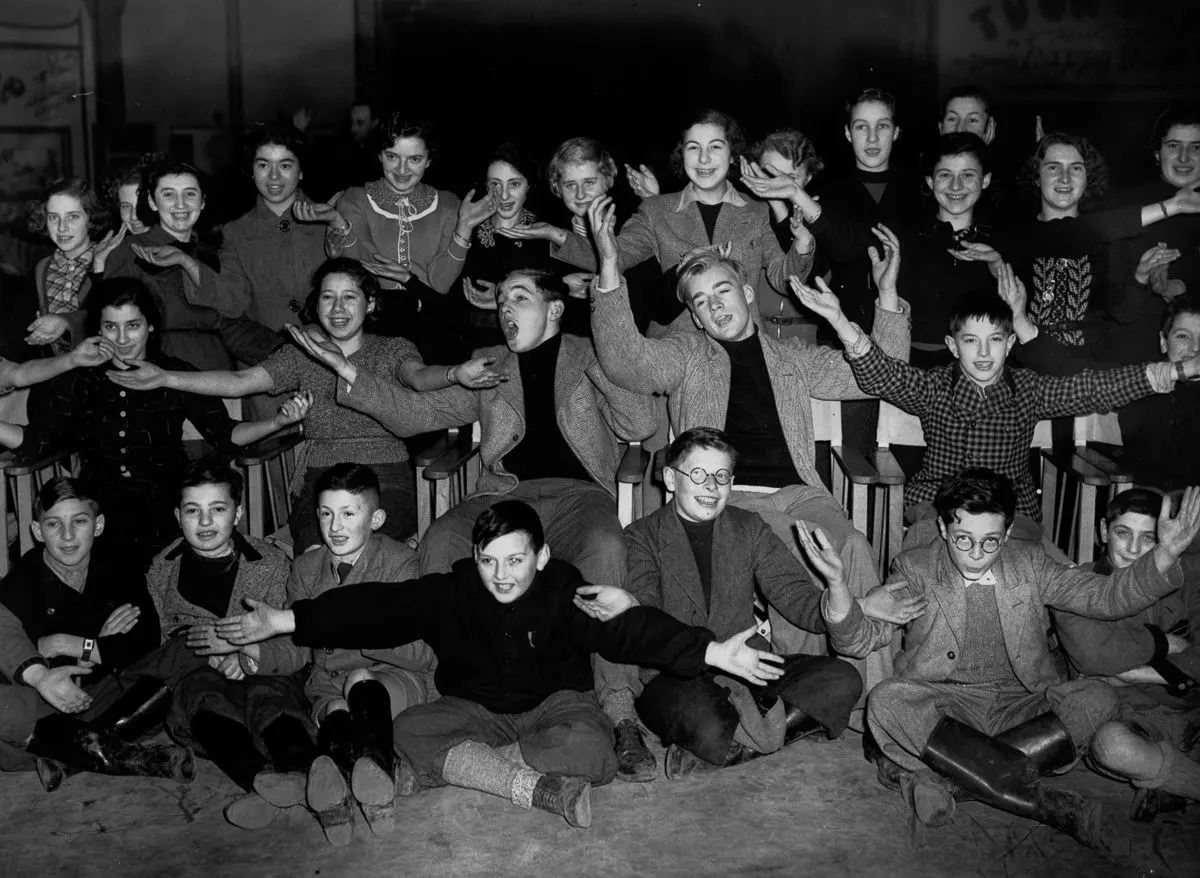 Two Etonian schoolboys give singing lessons to a group of Jewish refugees at Dovercourt holiday camp, 1939.