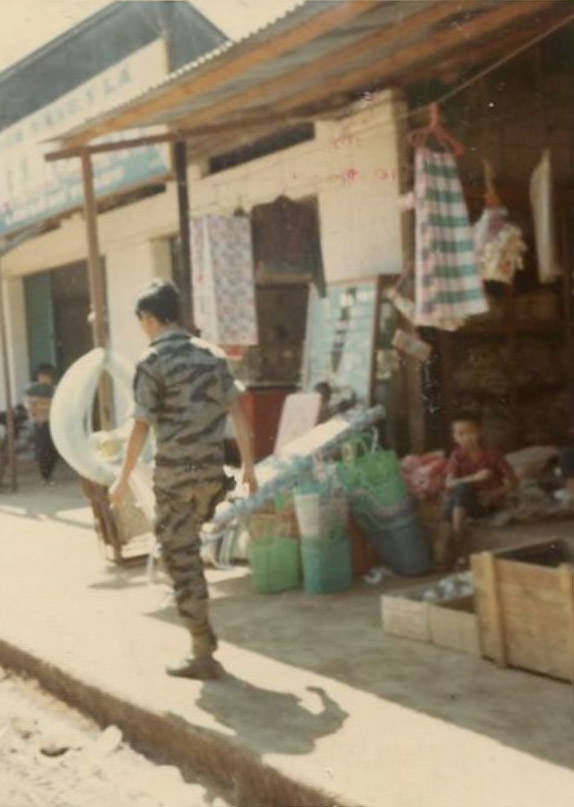 An unidentified South Vietnamese Army (ARVN) soldier walking past a store somewhere in the city of Bồng Sơn in South Vietnam.