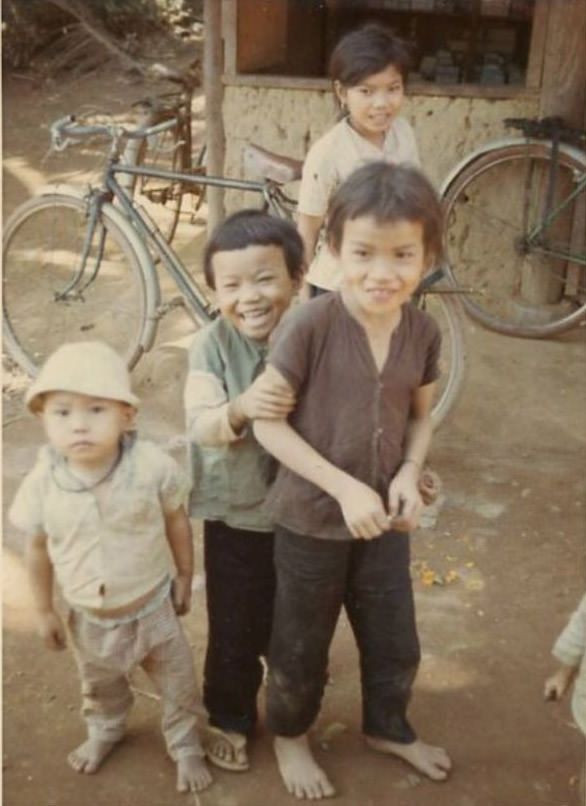 Vietnamese children laughing outside in a Vietnamese village, as they pose for the camera of an unidentified U.S. Army soldier.