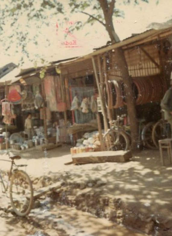A sidewalk scene with stores, including a bicycle shop, in a Vietnamese market in the city of Bồng Sơn in South Vietnam.