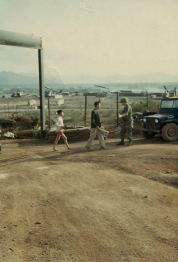 A Vietnamese man and boy, treated as prisoners, walking along being stopped by an Army soldier in the 2nd Battalion.