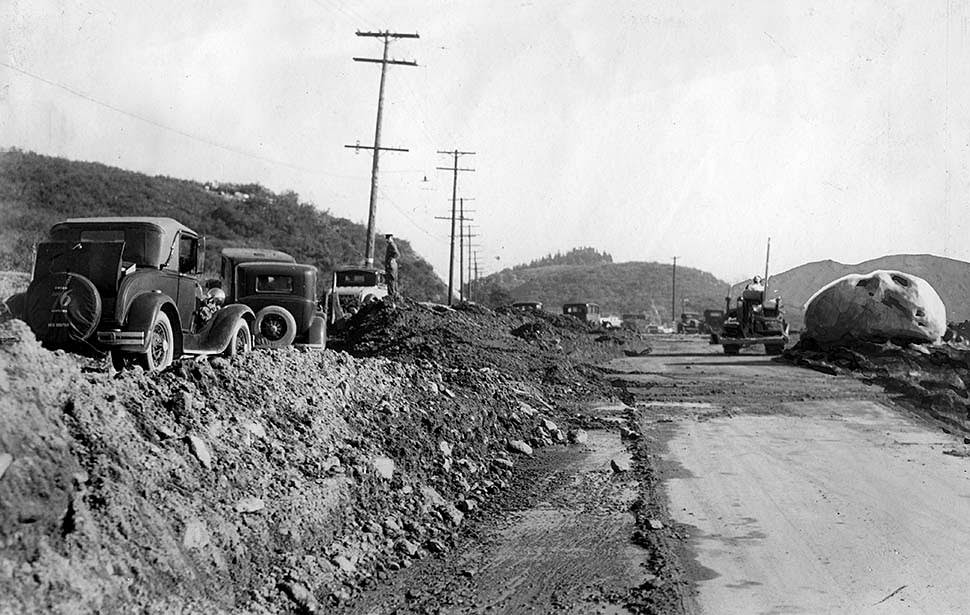 Cars parked on the dirt, left, show the depth of debris on roadway being cleared on Foothill Boulevard in Montrose, 1934