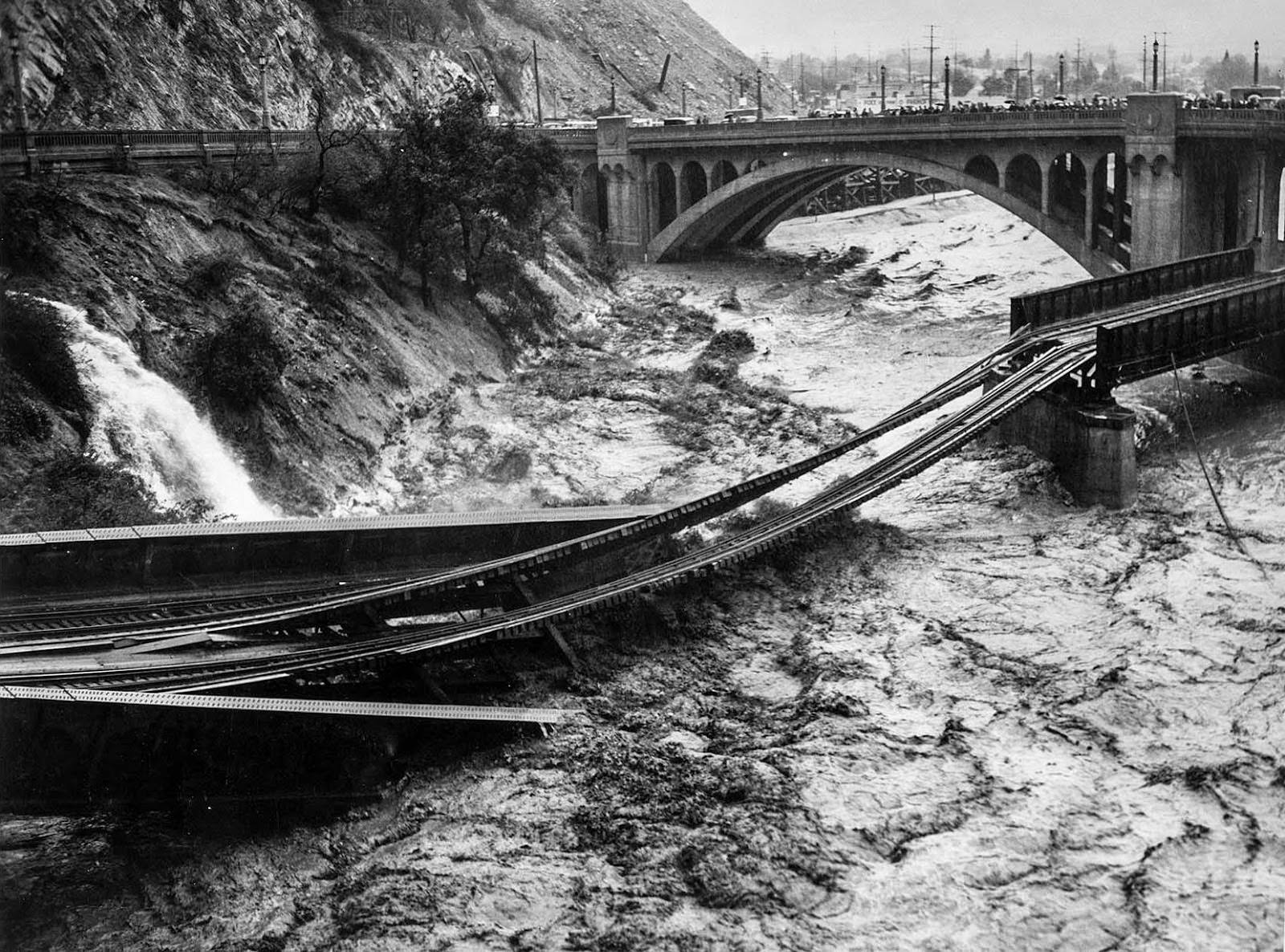 Floodwaters in Los Angeles River destroy Southern Pacific railroad bridge. The photo was taken from North Figueroa Street bridge, 1938