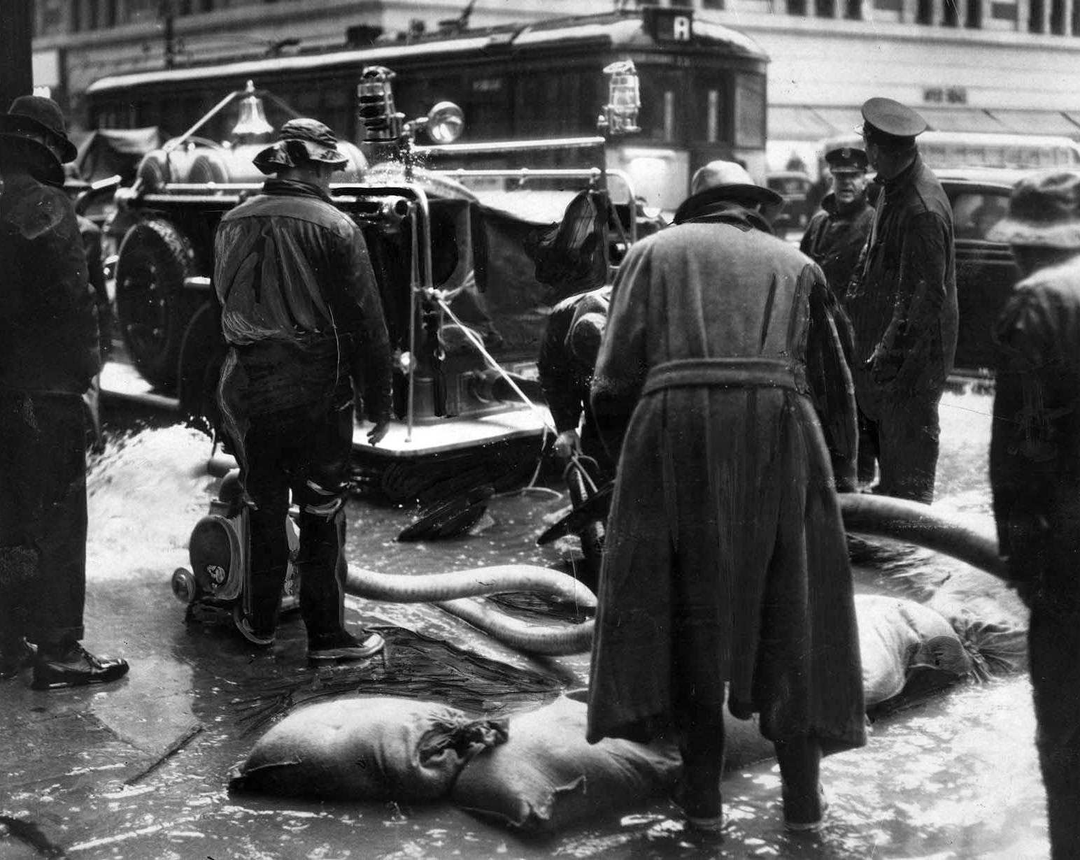 Water rising above the drain level in underground conduits threatened telephone service in downtown Los Angeles. Fire Department pumpers answered the call, 1938