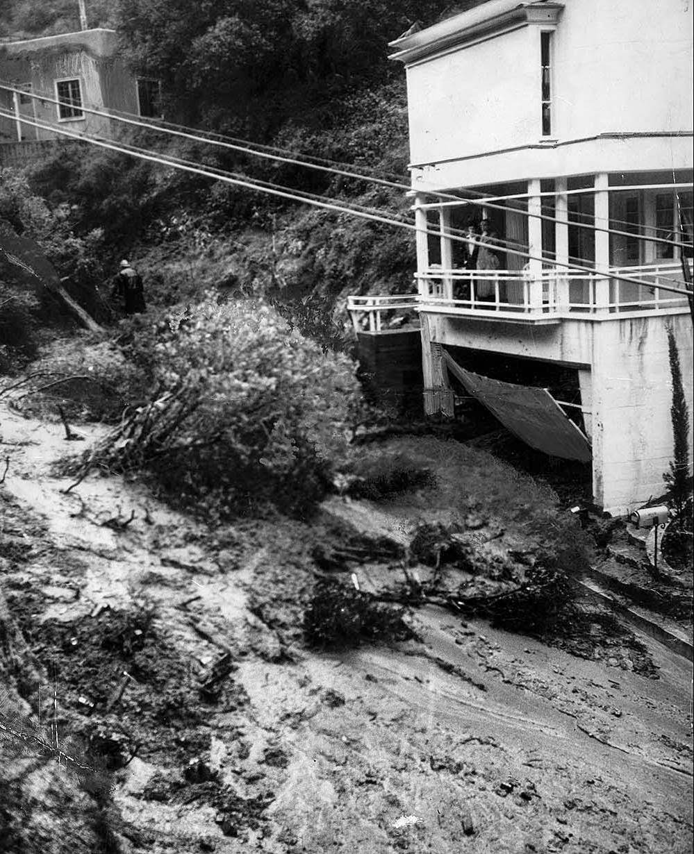 Water-soaked earth moved rapidly down the side of Laurel Canyon at Kirkwood Avenue, carrying trees and boulders in its path and wrecking the basement garage of this home, 1938