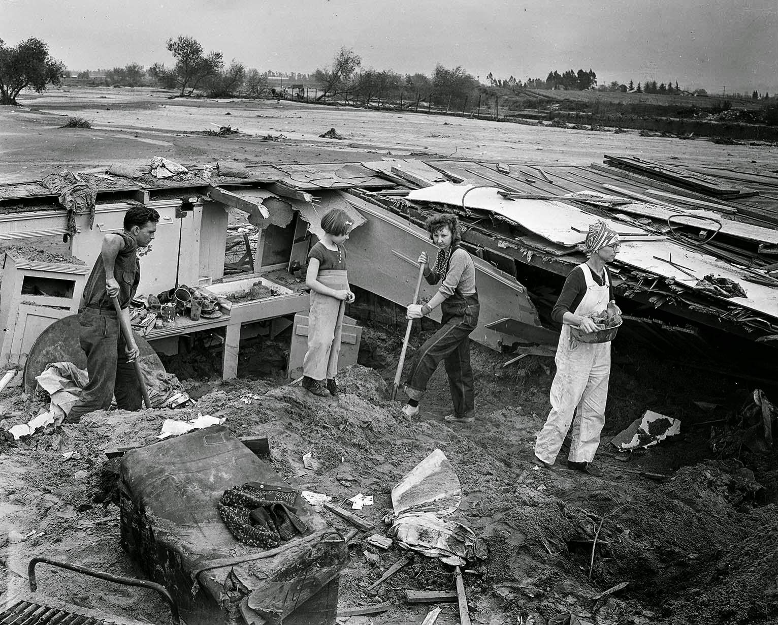 Mr. and Mrs. J. L. Smith, their daughter and 5-year-old granddaughter at Burbank and Ethel Streets in Van Nuys begin the task of digging out their home, 1938