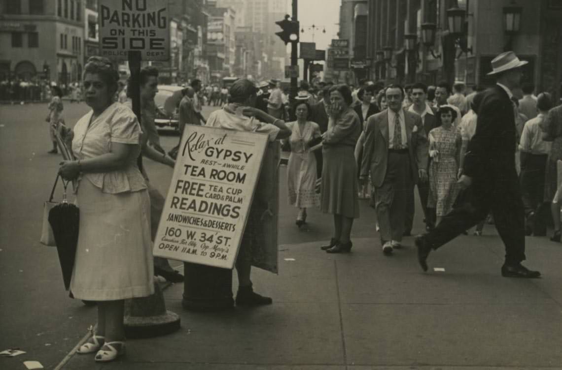 A man wears a sandwich board sign for Gypsy Tea Room on a busy street in Midtown Manhattan, 1950