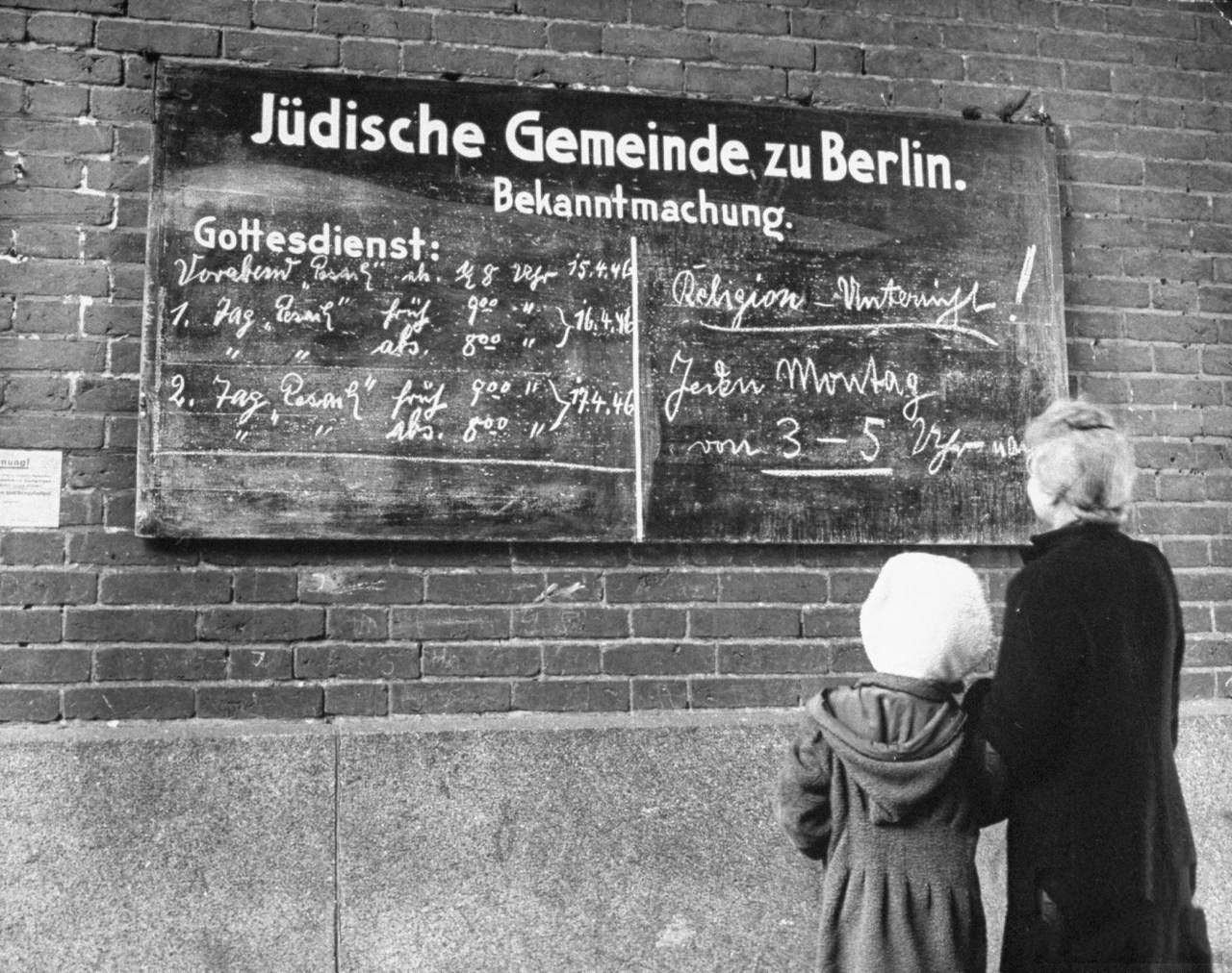 A woman and her child reading the bulletin board outside a synagouge during Passover.