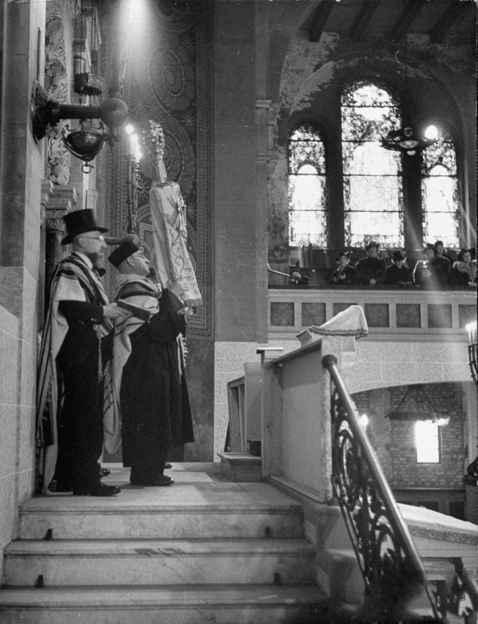 Chief Cantor Ruschin holding Torah scrolls up to the worshipers at the synagogue during Passover.