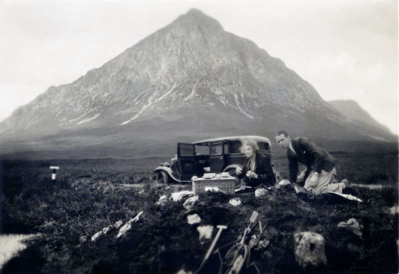 A stylish couple enjoying a picnic on a windy day in the Scottish Highlands near Buachaille Etive Mòr mountain, 1932