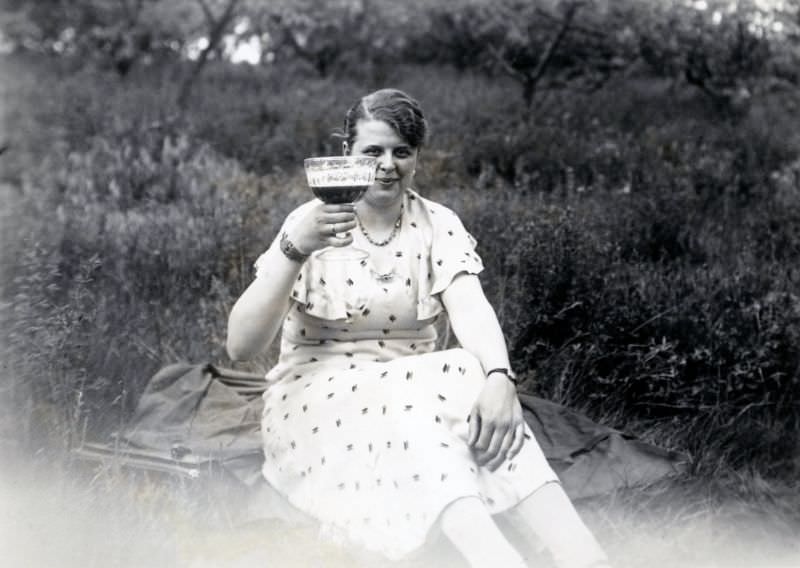 A young lady raising her glass in a meadow in the countryside, 1935
