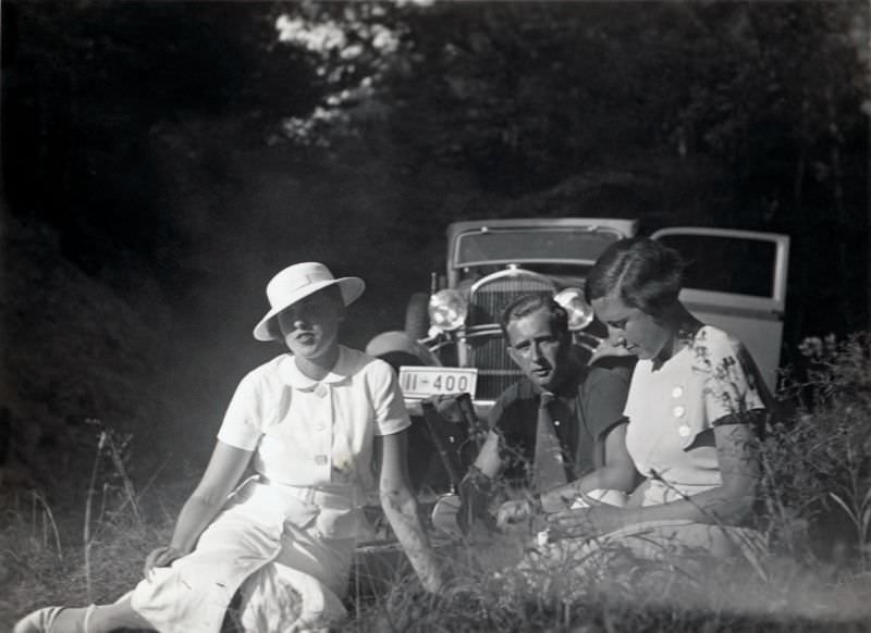 Two stylish young ladies and a fellow enjoying a picnic in the countryside, 1935