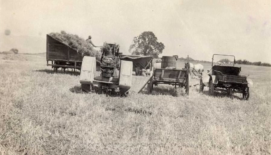 Automobile, tractor, and hay-filled cart in a field in Evergreen, near San Jose, California, 1920