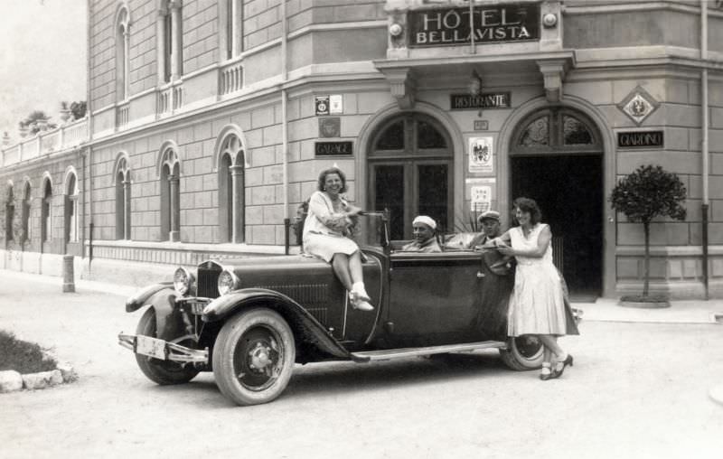 Two ladies in white dresses and two fellows with flat caps posing in front of Hotel Bellavista in the Italian holiday resort of Riva del Garda, 1930