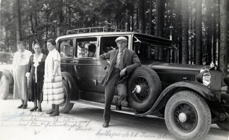 Three elderly ladies and a dapper fellow in a suit posing with a Steyr XVI on the side of a gravelled road in summertime, June 28, 1931