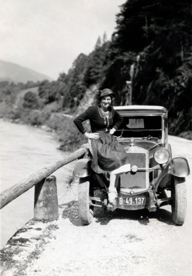 A lady wearing the traditional Alpine dress known as Dirndl posing with a Steyr XII on a gravel road in the countryside, 1933