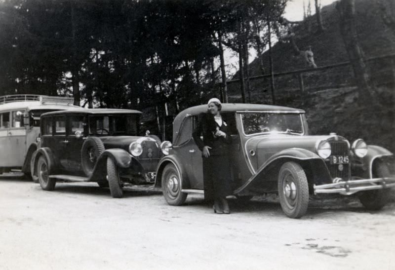 An elegant lady posing with a Steyr 30 Sport-Cabriolet on the side of a gravel road in the countryside, 1935