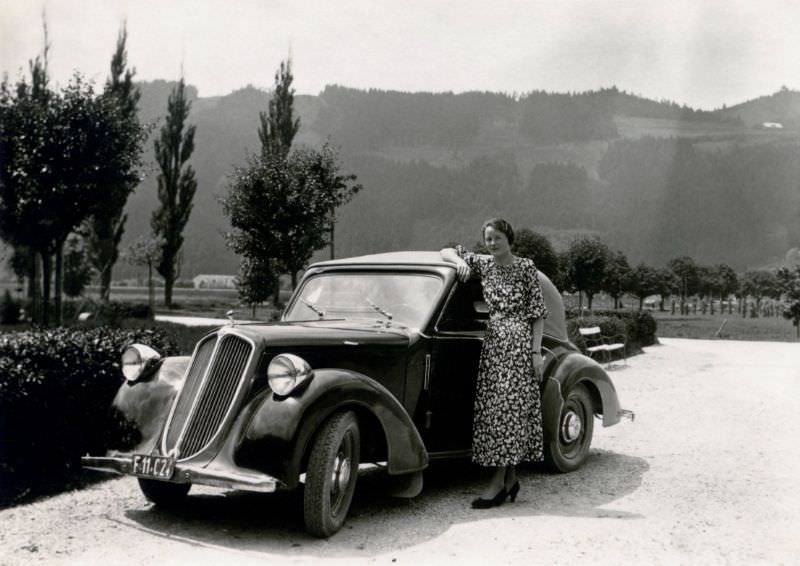 An elegant young lady in a floral summer dress posing with a Steyr 100 Cabriolet in the countryside, 1936