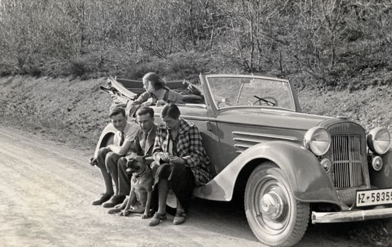 A company of four and their pet boxer posing with a Steyr 530 Cabriolet in the countryside, 1938