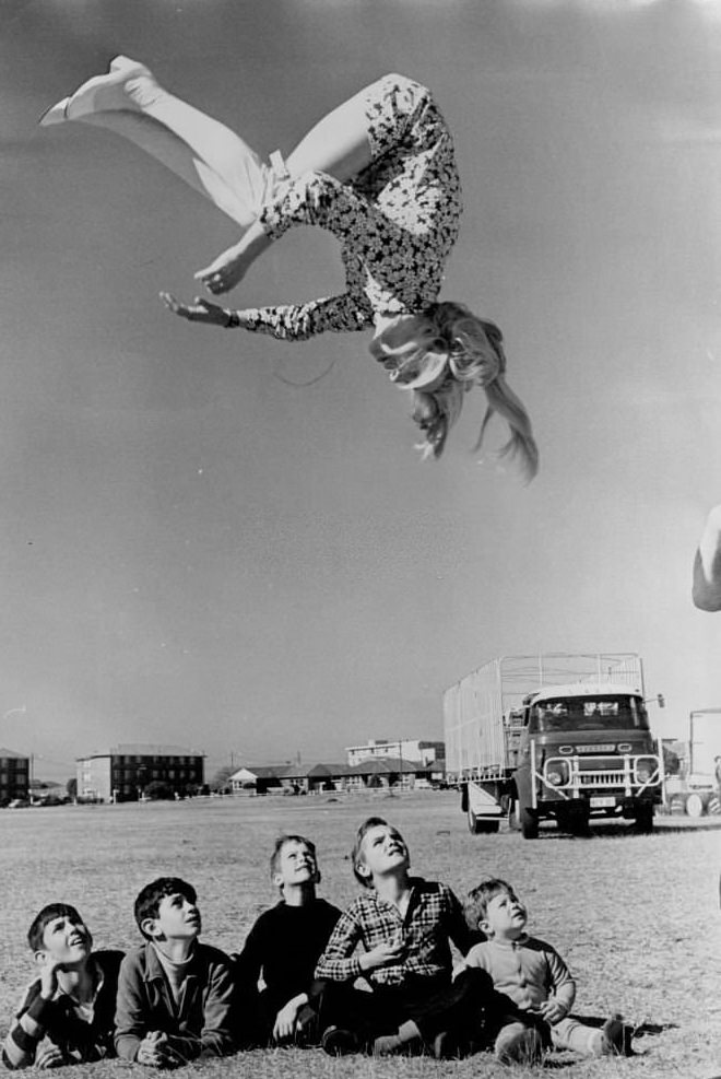 Flying Trapeze performer Nikki Ashton thrills children with a flying back somersault in the sunshine at Rowland park, Kingsford.