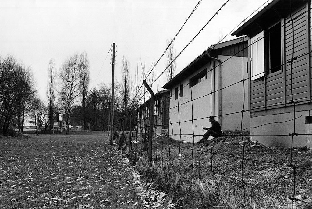 An Italian emigrant reading a letter among cabins surrounded by barbed wire. Zurich, 1971