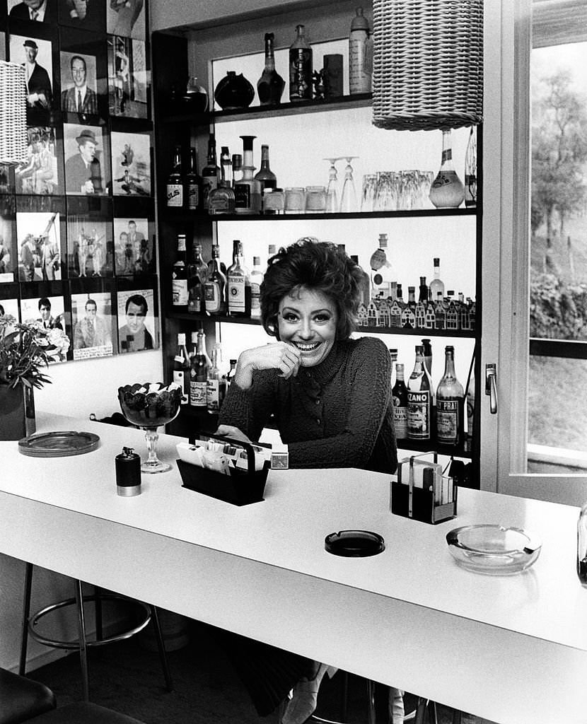 Italian singer, actress and showgirl Caterina Valente sitting in the bar area at home, Arosio, 1970