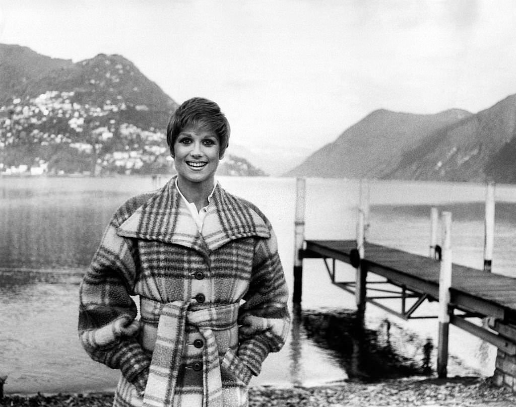 British showgirl Minnie Minoprio (Virginia Minoprio) smiling on the lake shore wearing a tartan coat, Lugano, 1970s.
