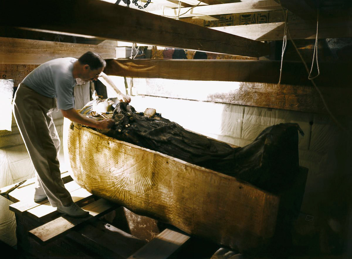 Howard Carter working on the lid of the second (middle) coffin, still nestled within the case of the first (outermost) coffin in the Burial Chamber. Tutankhamun's Tomb, October 1925