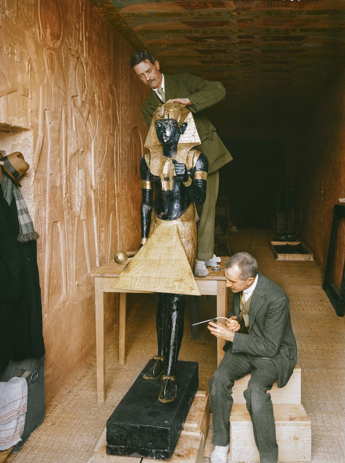 Arthur Mace (standing) and Alfred Lucas (sitting) working inside the makeshift 'laboratory' (set up in KV 15, the tomb of Sethos II) on the conservation of one of the two sentinel statues from the Antechamber (Carter no. 22). Sethos II's Tomb, 4th January 1923