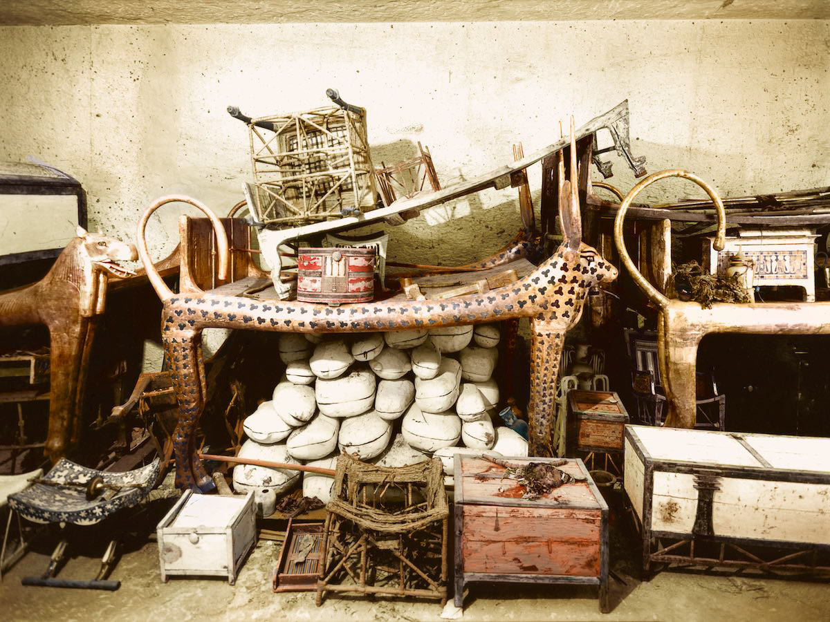 Objects, including the cow-headed couch (Carter no. 73) and boxes containing joints of meat (Carter nos. 62a to 62vv) piled up against the west wall of the Antechamber. Tutankhamun's Tomb, December 1925