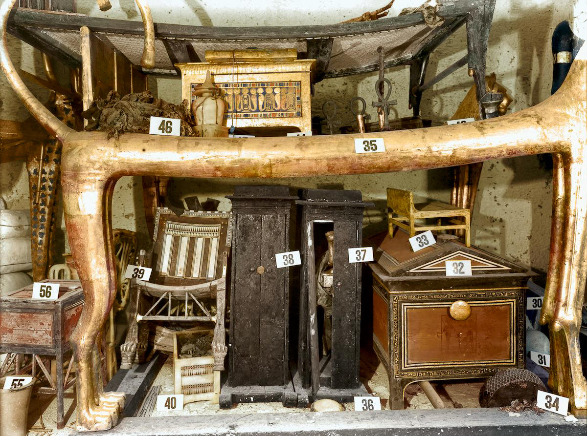 Objects stacked under the lion couch (Carter no. 35) against the west wall of the Antechamber. Tutankhamun's Tomb, December 1925