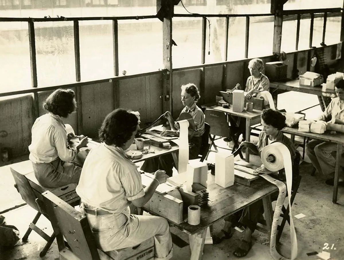 Paper chopping. At these choppers, each letter is handcut from the roll and here the culls or bad letters are pulled out.