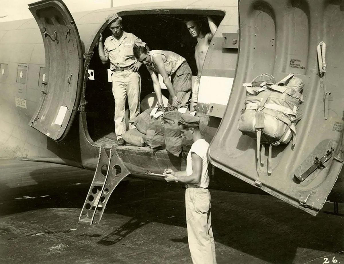 The final act at the airstrip with the mail truck, containing letters for the States and for the troops, pulled alongside the plane. Port Moresby, Papua New Guinea, 1944.