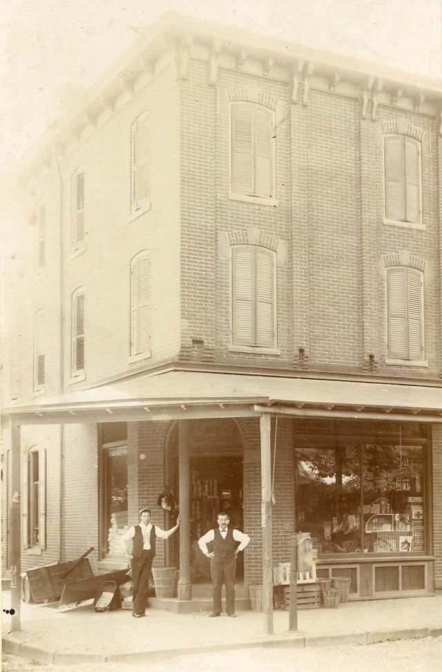 Two men outside corner general store, 1880s