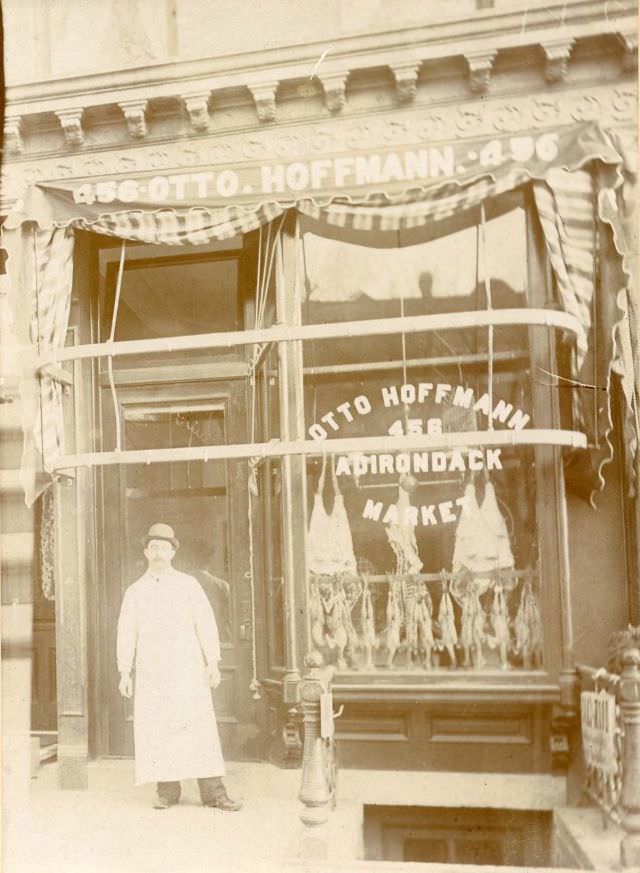 Butcher standing outside Otto Hoffmann Adirondack Market, 1890s