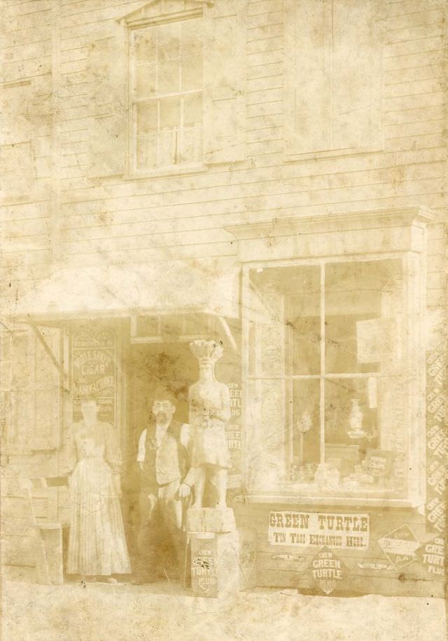 Man and woman outside tobacconist shop, 1880s
