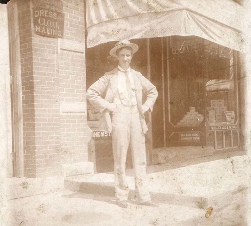 Man outside dress and cloak making shop, Gloversville, New York, 1880s