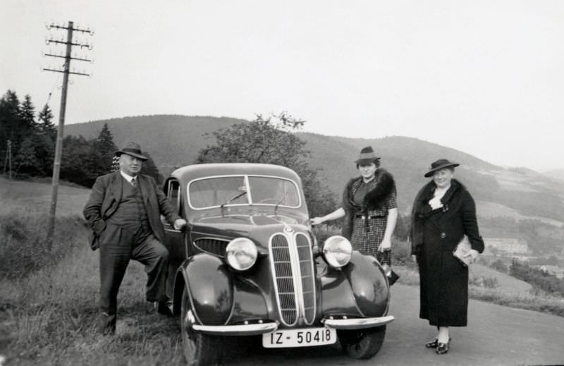 A company of three posing with a BMW 320 in the countryside, 1938.