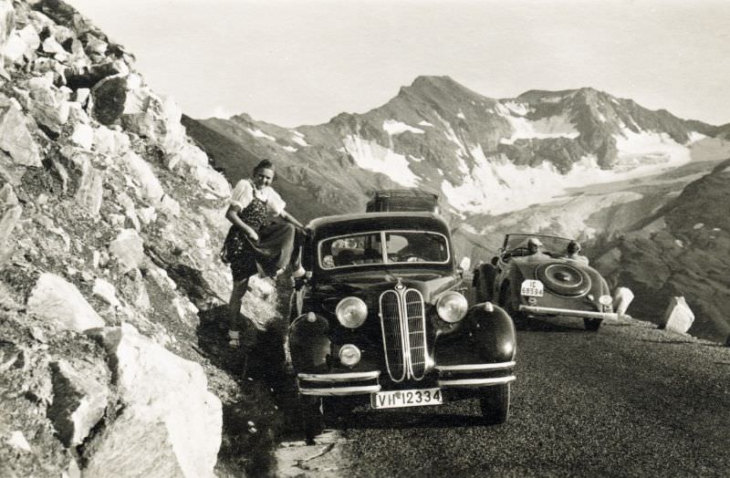 A young lady enthusiastically posing with a BMW 326 on a mountain road. She is wearing the traditional Alpine dress known as Dirndl, 1938.