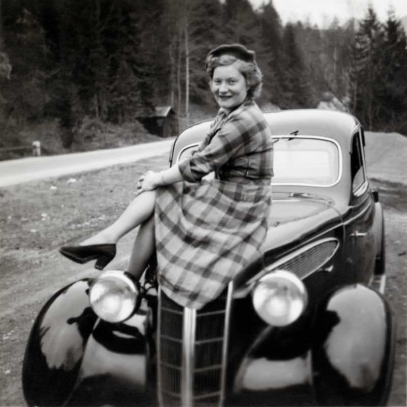 A young lady seductively posing on the bonnet of a BMW 326 by the side of a country road, 1938.