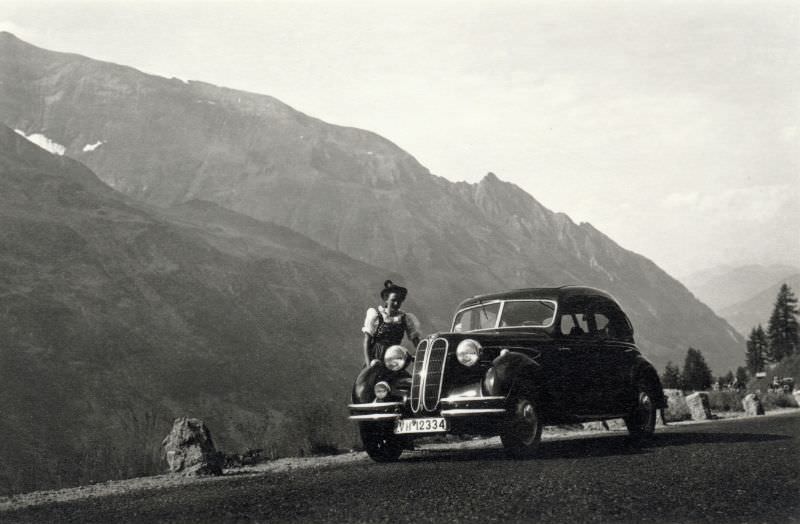 A young lady wearing a Dirndl posing with a BMW 326 on an Alpine road, 1938.